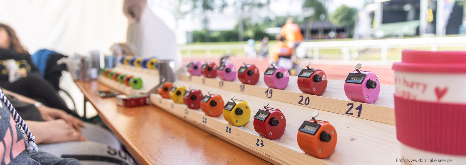 Handzähler auf einem Tisch bei der Organisation des 24-Stunden-Rollstuhlrennens in Eislingen. Die farbigen Zählgeräte werden zur Erfassung von Runden und Ergebnissen während des inklusiven Sportevents eingesetzt.