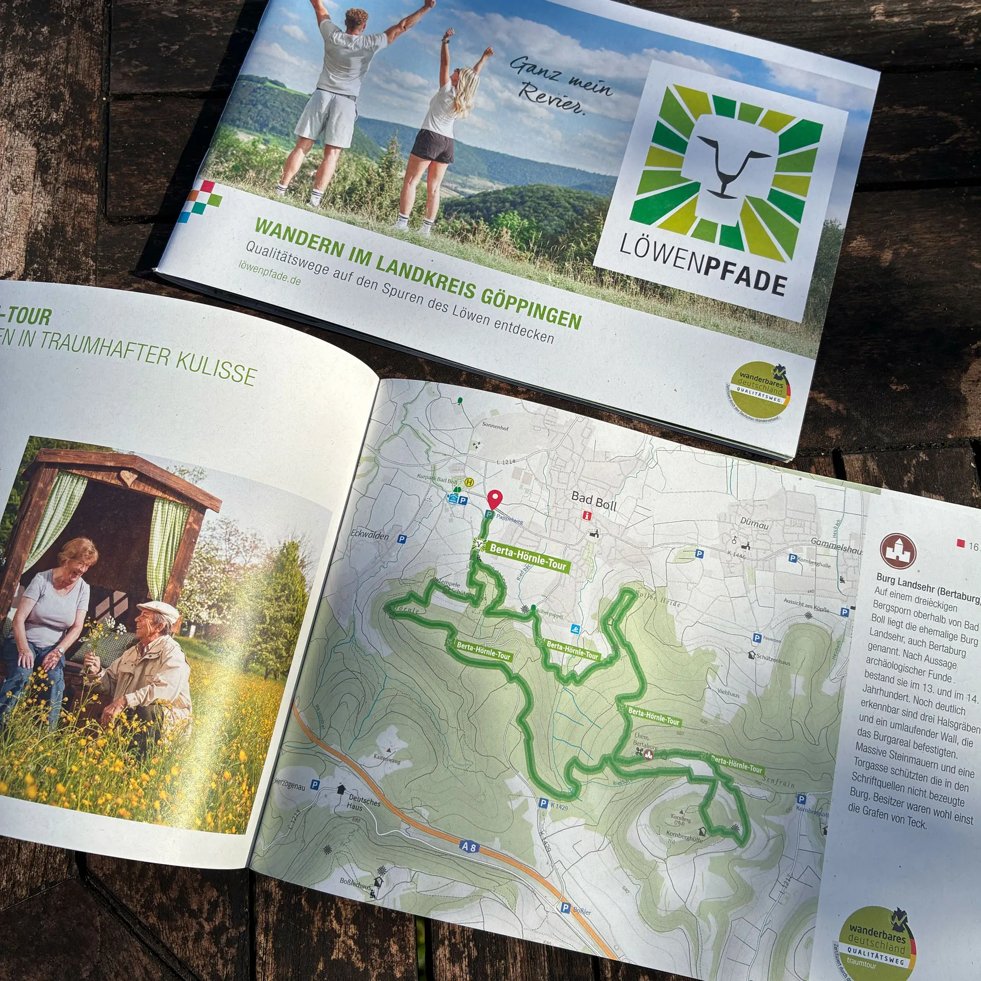 Geöffnete Wanderbroschüre von Löwenpfade mit dem Titel 'WANDERN IM LANDKREIS GÖPPINGEN – Qualitätswege auf den Spuren des Löwen entdecken'. Das Cover zeigt zwei wandernde Personen auf einer Anhöhe mit dem Slogan 'Ganz mein Revier.' und dem Löwenpfade-Logo. Innen sind eine detaillierte Wanderkarte mit grün markierten Routen sowie Fotos von Natur und lokalen Motiven zu sehen.