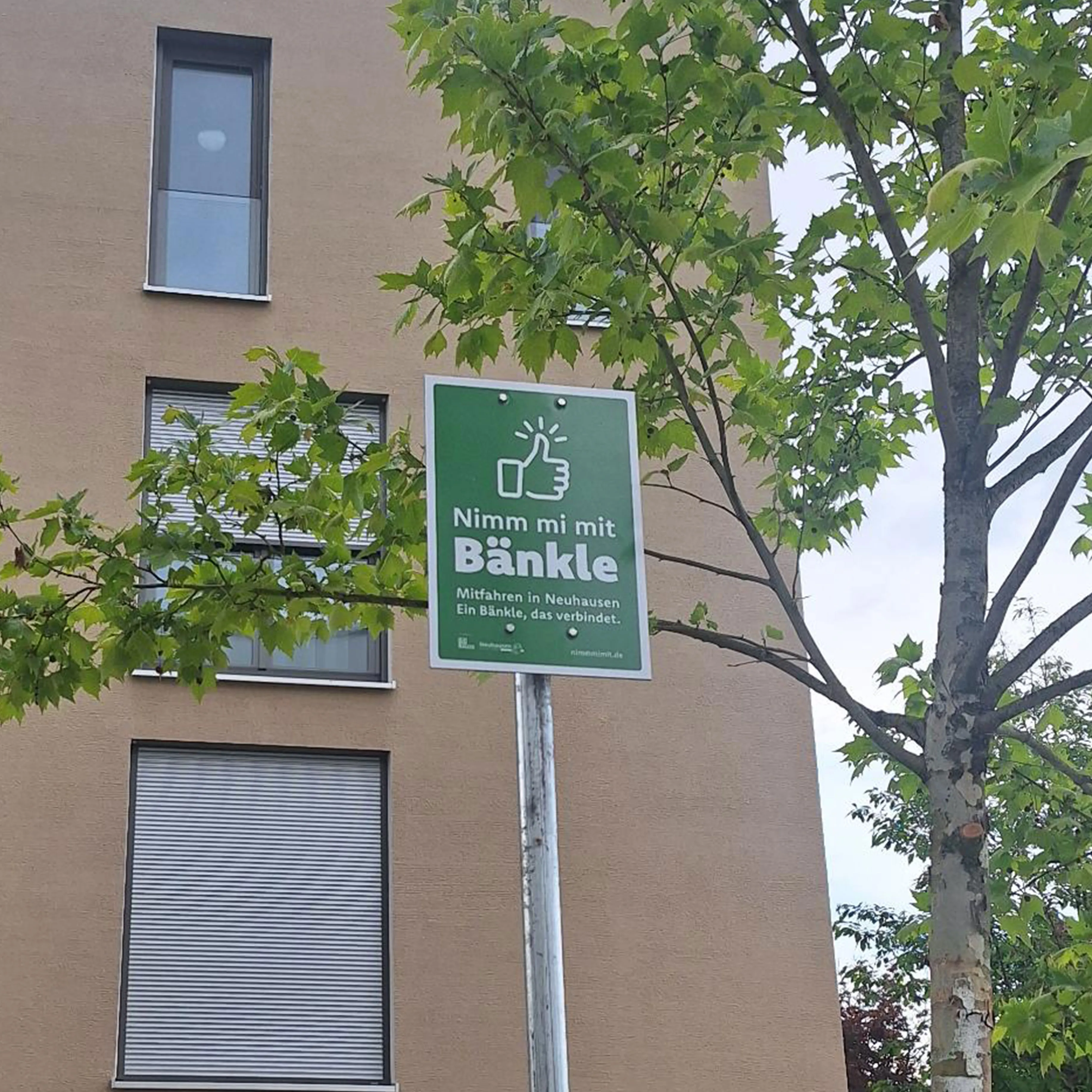 Standortschild der Mitfahrinitiative „Nimm mi mit Bänkle“ in Neuhausen auf den Fildern. Das grüne Schild kennzeichnet eine Mitfahrbank und unterstützt nachhaltige Mobilität sowie nachbarschaftliche Hilfe im Ort.