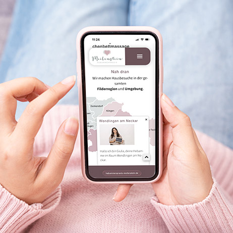 Smartphone mit responsiver Website der Hebammenpraxis Meilenstein. Auf dem Display ist die mobile Ansicht mit Standortkarte und Informationen zur Hebammenbetreuung in Filderstadt und Umgebung zu sehen.